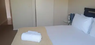 a bedroom with a large white bed with towels on it at Bougain Villas in Cape Town