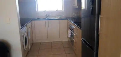 a kitchen with a sink and a black refrigerator at Bougain Villas in Cape Town