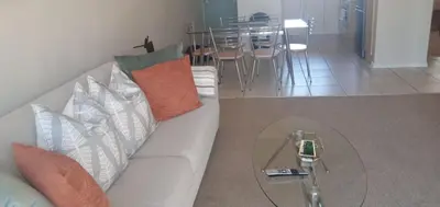 a living room with a white couch and a glass table at Bougain Villas in Cape Town