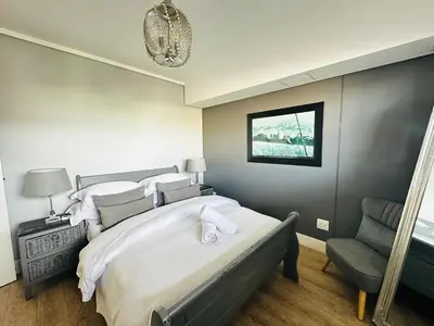a bedroom with a large bed and a chair at WATERS EDGE 103 in Cape Town