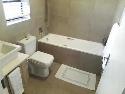 a bathroom with a toilet and a tub and a sink at WATERS EDGE 103 in Cape Town