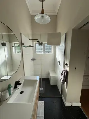 a bathroom with a tub and a sink and a mirror at Hartebeeskraal House in Paarl