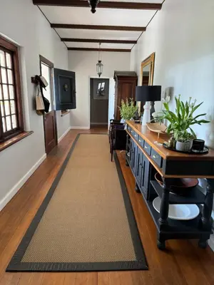 a hallway with a desk and a table with a rug at Hartebeeskraal House in Paarl