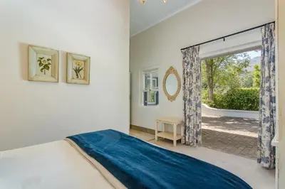 a bedroom with a bed and a large window at Franschhoek Rose Cottages in Franschhoek