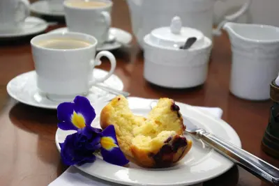 a plate with a pastry on a table with a cup of coffee at Lyngrove Wines & Guesthouse in Stellenbosch