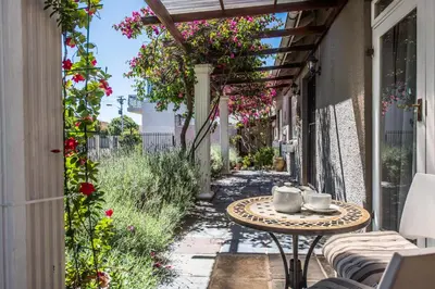 a patio with a table and flowers on a building at Greenlawns B&B in Cape Town