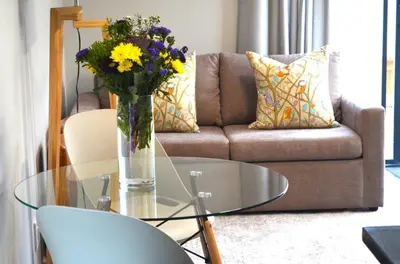a living room with a glass table with a vase of flowers at Columbine Place in Durbanville