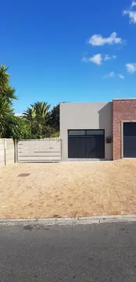 a brick parking lot with a building with two garage doors at Columbine Place in Durbanville
