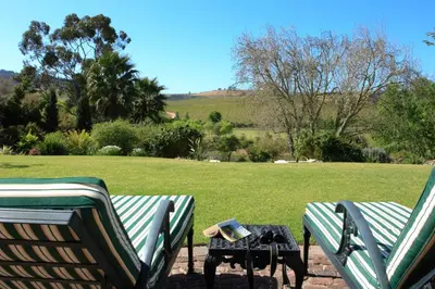 two lawn chairs and a table with a book on it at Sanddrif Stellenbosch Guest Farm in Stellenbosch