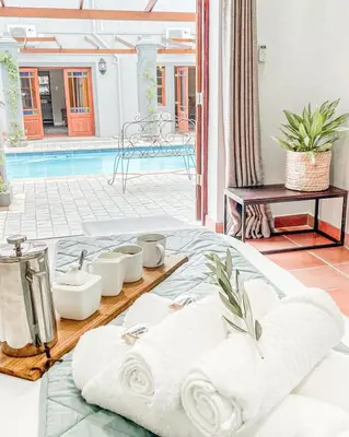 a table with white towels on a table with a pool at Olive Tree Boutique Hotel in Paarl
