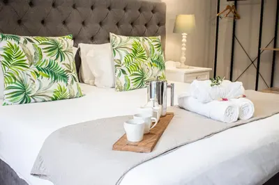 a bed with towels and a tray of mugs and towels at Olive Tree Boutique Hotel in Paarl