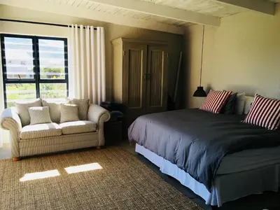 a bedroom with a bed and a couch and a window at Pringle @ 865 Jally in Pringle Bay