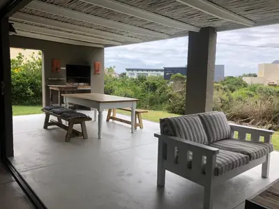 a patio with a table and a chair and a bench at Pringle @ 865 Jally in Pringle Bay