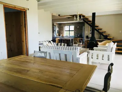 a dining room with a wooden table and white chairs at Pringle @ 865 Jally in Pringle Bay