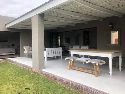 a patio with a table and two benches on it at Pringle @ 865 Jally in Pringle Bay