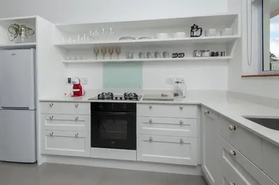 a kitchen with white cabinets and a black stove top oven at Perla in Hermanus
