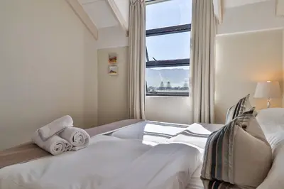a bedroom with a bed with towels and a window at Whale Coast All-Suite-Hotel - DCC Hotel Group in Hermanus