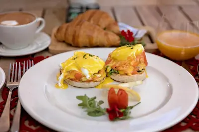 a white plate with two eggs sandwiches and a cup of coffee at Holden Manz Country House in Franschhoek