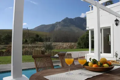 a table with two glasses of wine and a bowl of fruit at Charming Villa in Stellenbosch