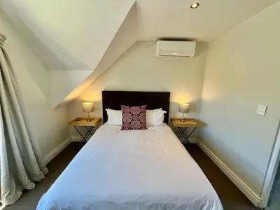 a bedroom with a white bed with two night stands at Charming Villa in Stellenbosch