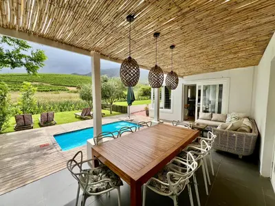 a dining room with a wooden table and chairs at Charming Villa in Stellenbosch