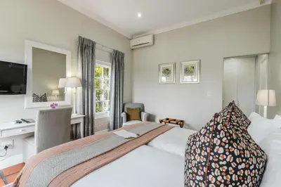 a hotel room with a large bed and a desk at Eikendal Lodge in Stellenbosch