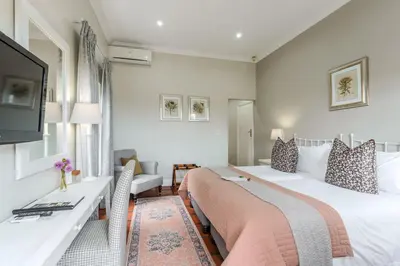 a hotel room with two beds and a television at Eikendal Lodge in Stellenbosch