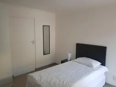 a bedroom with a white bed and a mirror at Fama Lodge Single Rooms in Cape Town