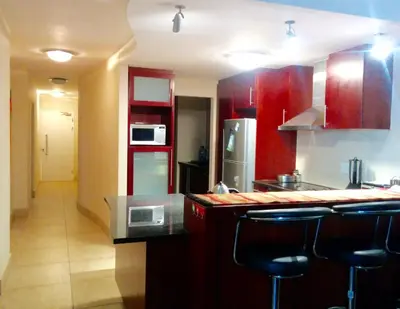 a kitchen with red cabinets and black counter tops at Ocean View Luxury Self-Catering in Strand