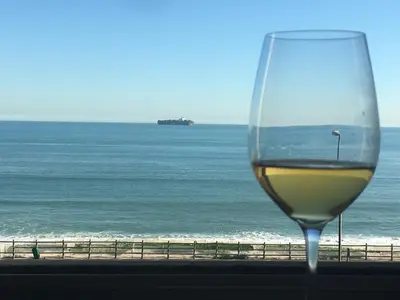 a glass of wine sitting on a ledge overlooking the ocean at Zeezicht 303 in Bloubergstrand