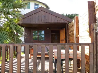 a wooden cabin with a porch on a deck at Cape Oasis Guesthouse in Bloubergstrand