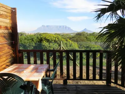a table and chairs on a porch with a view of mountains at Cape Oasis Guesthouse in Bloubergstrand