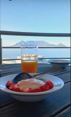 a plate of food and a glass of beer on a table at Ocean View B1001, Blouberg in Bloubergstrand