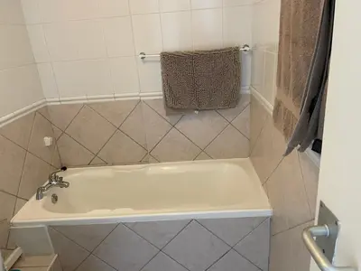 a white tub in a bathroom with a towel on the wall at Ocean View B1001, Blouberg in Bloubergstrand
