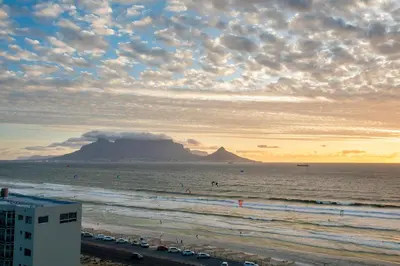 a view of the beach with table mountain in the background at The Waves Blouberg Beach Apartments in Bloubergstrand