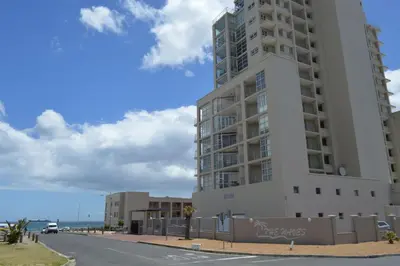 a tall white building on the side of a street at The Waves Blouberg Beach Apartments in Bloubergstrand