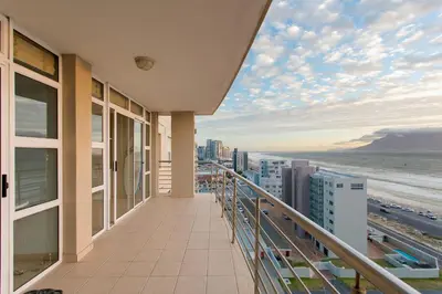 a balcony with a view of the beach and buildings at The Waves Blouberg Beach Apartments in Bloubergstrand
