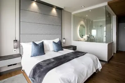 a bedroom with a large white bed and a large mirror at Bayview 303 in Hermanus
