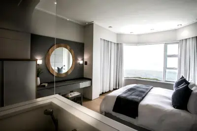 a bedroom with a large bed and a mirror at Bayview 303 in Hermanus