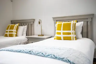 a bedroom with two beds with yellow and white pillows at Bayview 303 in Hermanus