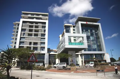 two tall buildings with cars parked in front of them at The Residences at Crystal Towers in Cape Town