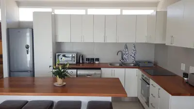 a kitchen with white cabinets and a wooden counter top at 604 St Tropez in Strand