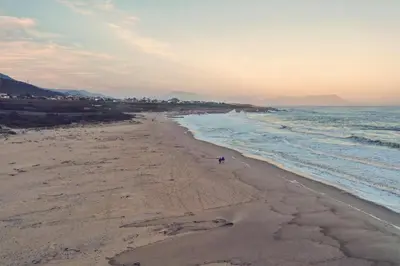 a beach with a person walking on the sand at 36 Df Strauss Street in Kleinmond