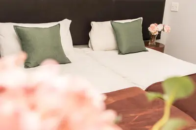 a bed with green pillows and a vase of flowers at Mauya Guesthouse in Kuilsrivier