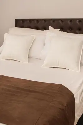 a bed with white pillows and a black headboard at Mauya Guesthouse in Kuilsrivier
