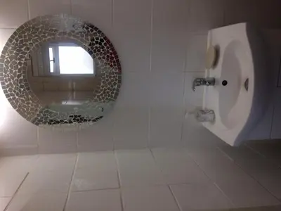 a bathroom with a circle mirror and a urinal at Romilly Beach Apartment in Strand
