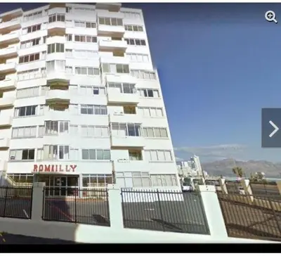 a tall white building with a sign on it at Romilly Beach Apartment in Strand