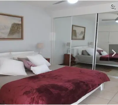 a bedroom with a large bed and a mirror at Romilly Beach Apartment in Strand