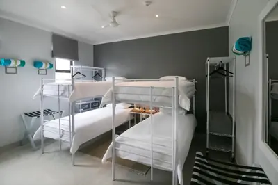 a bedroom with two bunk beds with white sheets at Zzzone Boutique Hostel in Hermanus