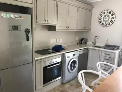 a kitchen with white cabinets and a washer and dryer at Maison Malherbe in Franschhoek